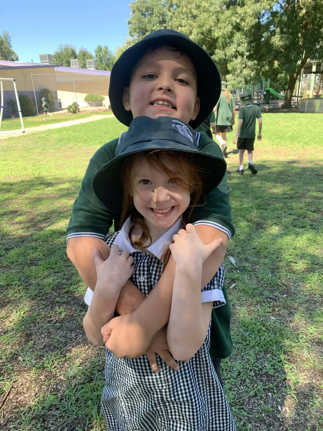 An older Carra student giving a younger student a hug in the school grounds